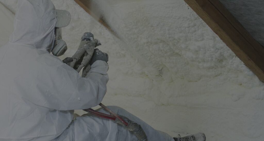 Insulation installer applying spray foam insulation in a building.