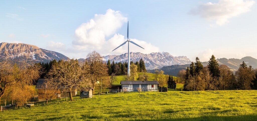 Wind turbine in a rural landscape with mountains in the background.