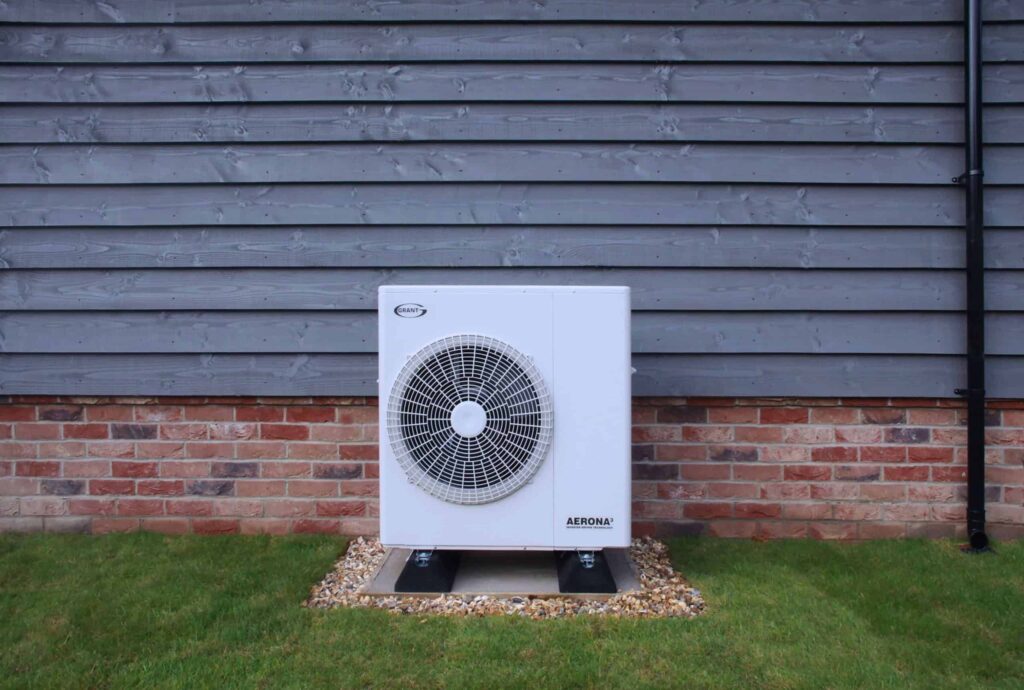 Modern energy storage unit installed outdoors against a wooden and brick wall.