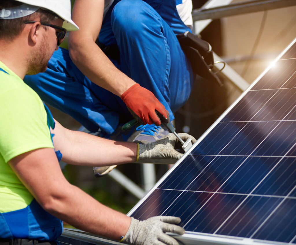 Solar panel installation by technicians in safety gear at a renewable energy site.