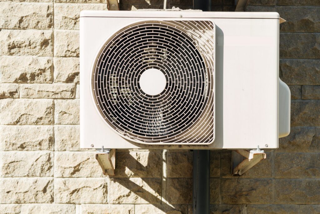 Modern heat pump outdoor unit installed on brick wall for efficient heating and cooling.