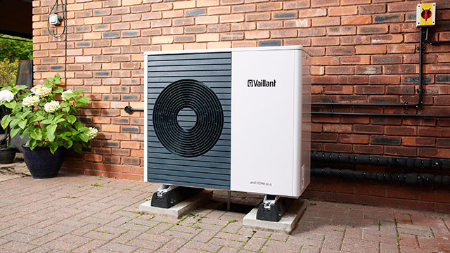Modern Vaillant heat pump installed outdoors on a brick wall for renewable energy.