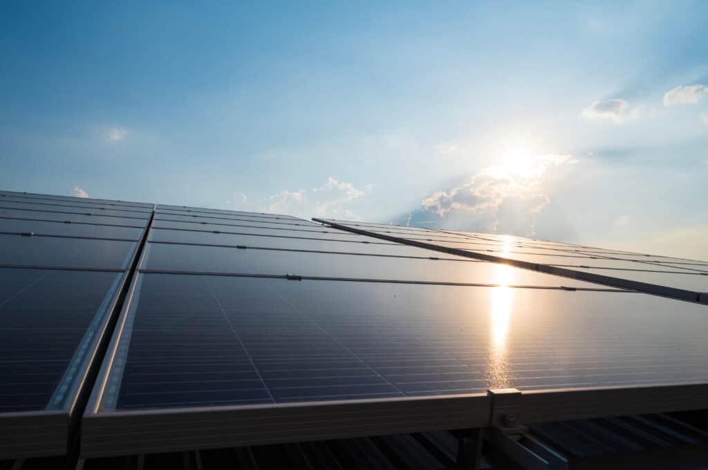 Solar panels installed on a building roof under a bright sun.
